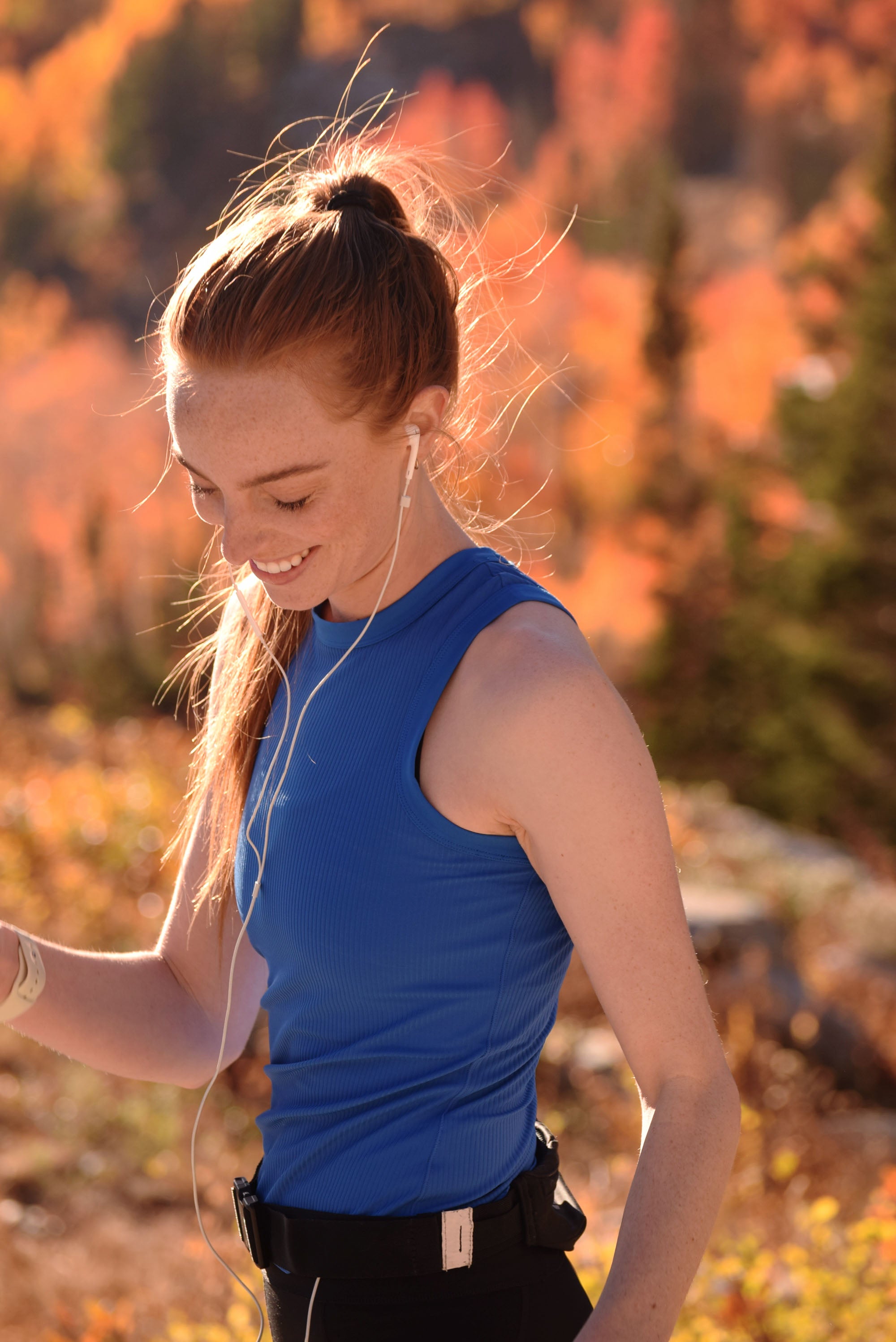 Woman in a blue sleeveless shirt outdoors with a blurred natural background