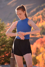 Woman in athletic wear checking her watch outdoors with a scenic background