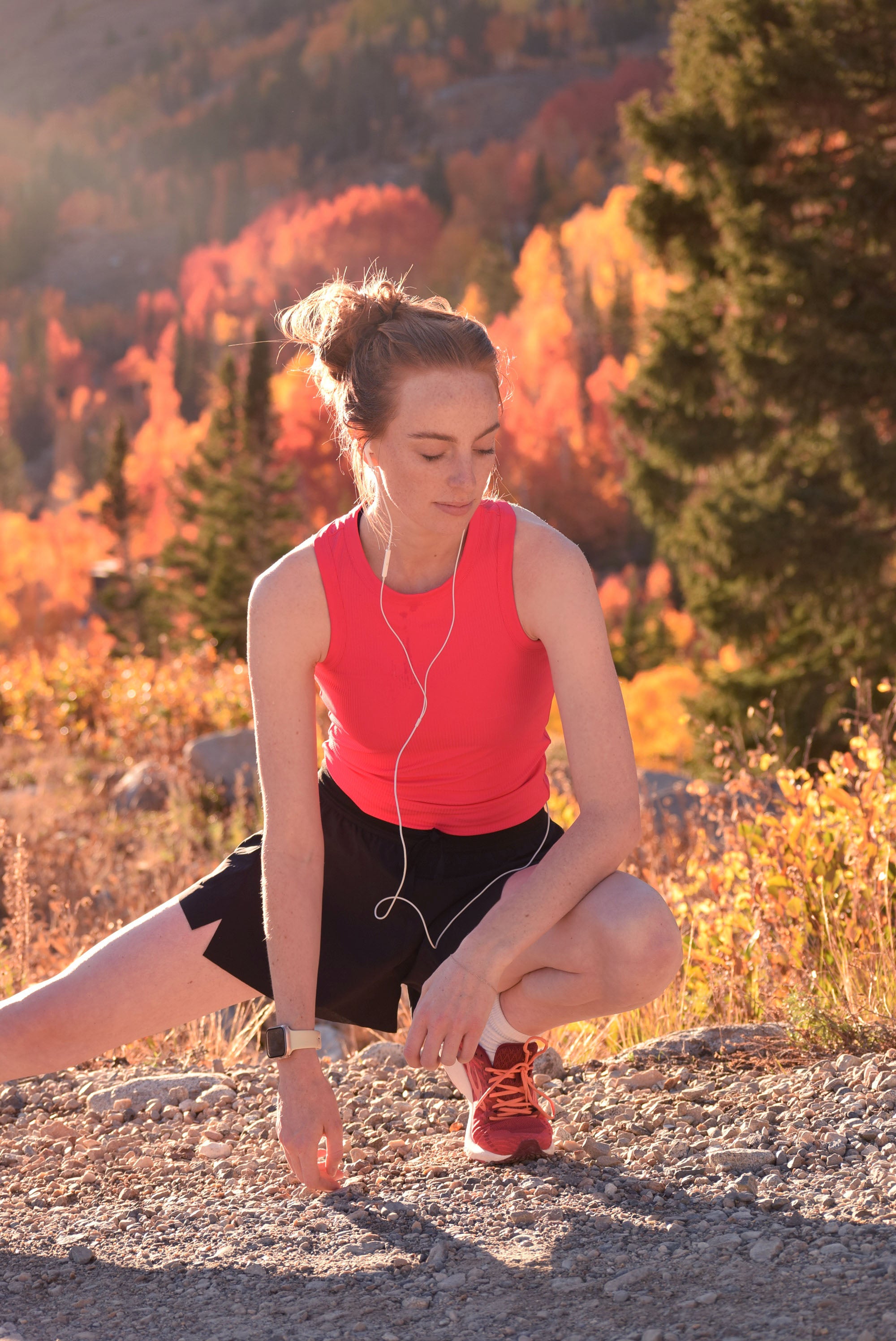 Woman stretching outdoors with autumn foliage in the background