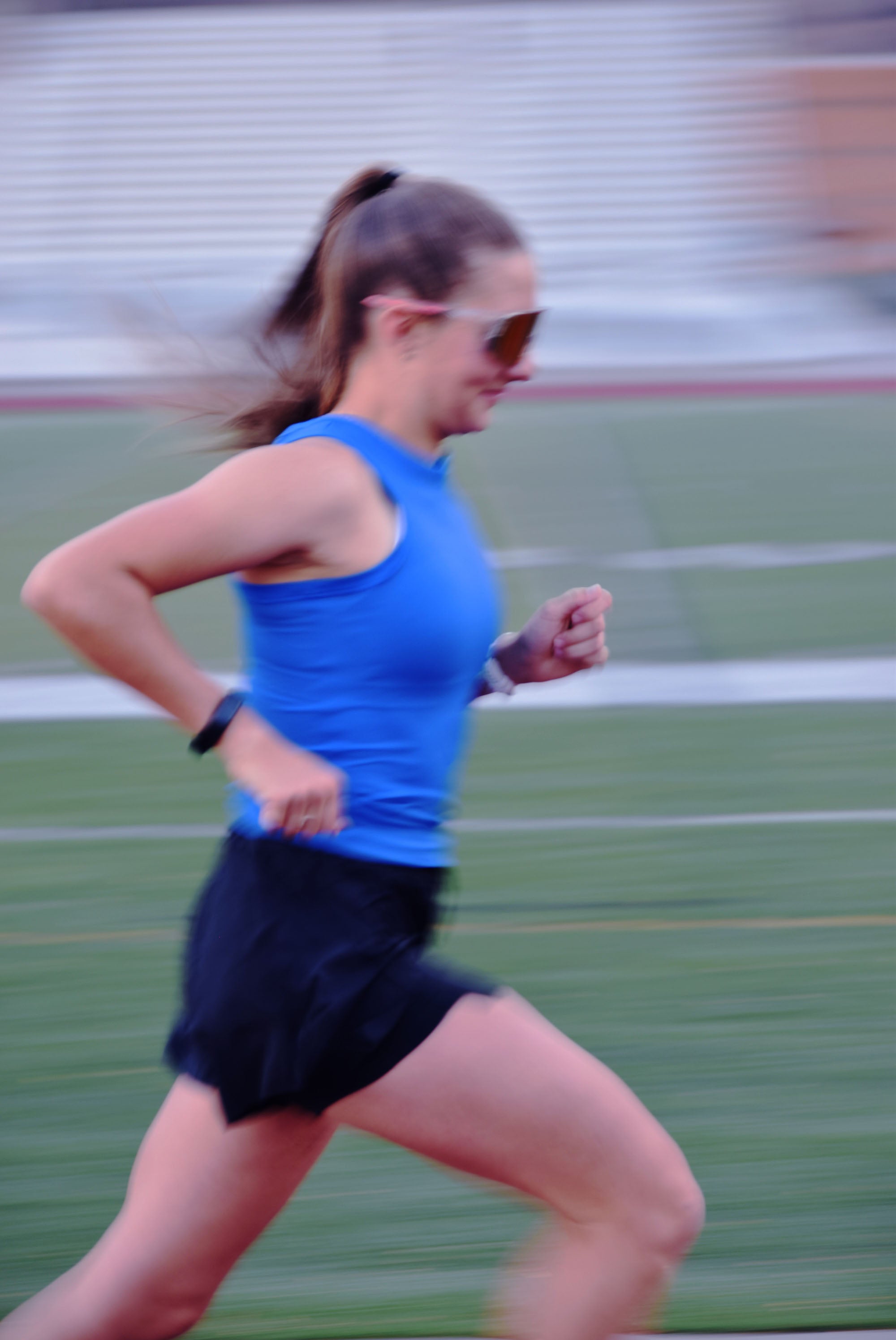 Person running on a track wearing a blue top and black shorts.